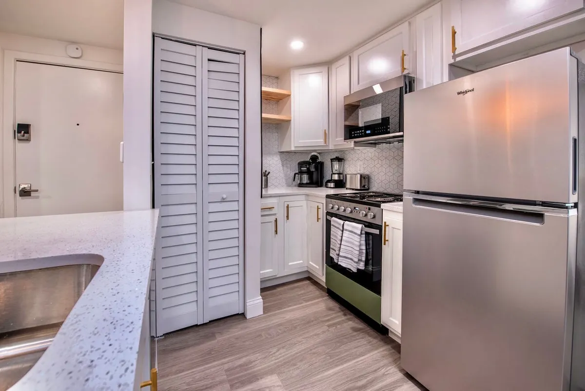 A cozy kitchen scene featuring prominent stainless steel appliances, including a refrigerator and a green stove. The kitchen island with a countertop is central, evoking a space for both cooking and gathering. The overall atmosphere suggests a space ideal for meal preparation and entertaining guests.