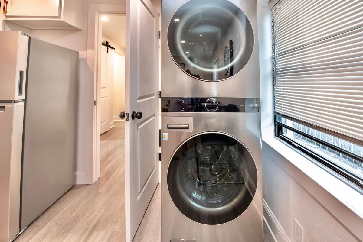 This image features a functional interior space showcasing a washer and dryer beside a window, with a refrigerator also in view. The area feels efficient and practical, emphasizing modern appliances and the convenience of in-home amenities.