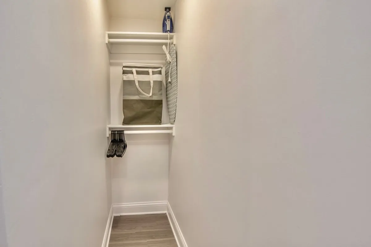 This image captures a minimalist storage area with a bag on a shelf, hanging items, and attractive flooring. The mood is organized and clutter-free, suggesting readiness for excursions or shopping trips.